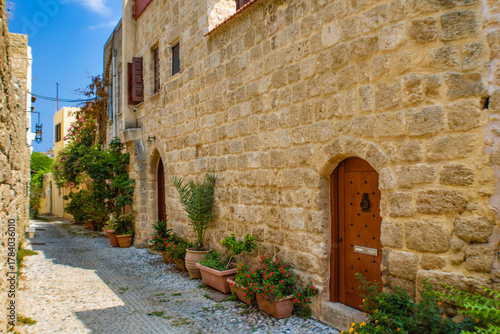 Fototapeta Naklejka Na Ścianę i Meble -  Narrow cobblestone alley  with stone walls in the Rhodes Old town, Greece
