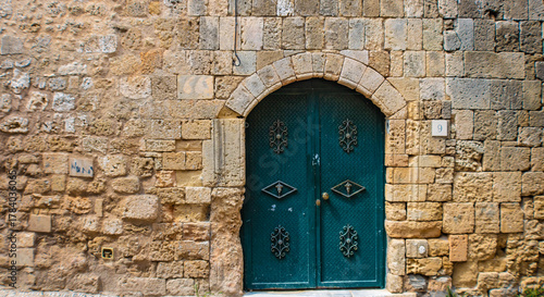 Fototapeta Naklejka Na Ścianę i Meble -  Beautiful old blue metal door on a stone wall in the Rhodes Old town, Greece