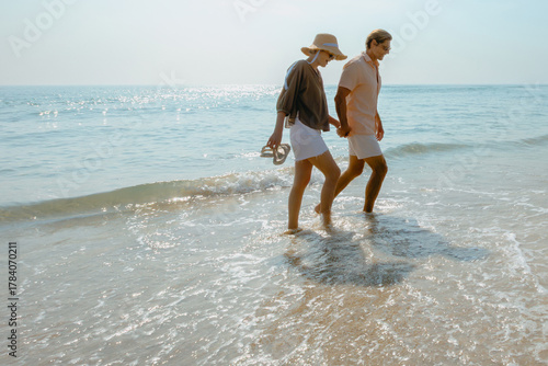 Young caucasian couple enjoying a beach walk by the ocean
