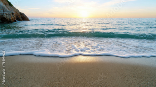 Fototapeta Naklejka Na Ścianę i Meble -  Sunset ocean wave on sandy beach with gentle foam and rocky headland