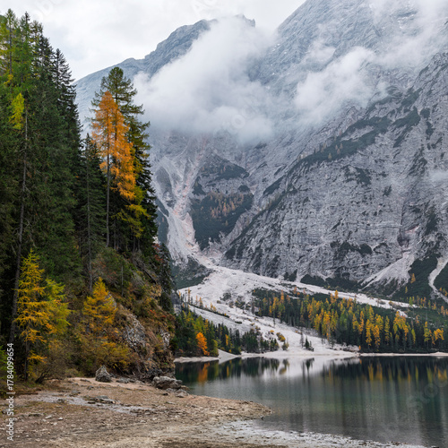 Mountain clear lake Braies, Dolomites, Italy. Landscape with high rocky mountains covered with forests and fog. Autumn landscape.
