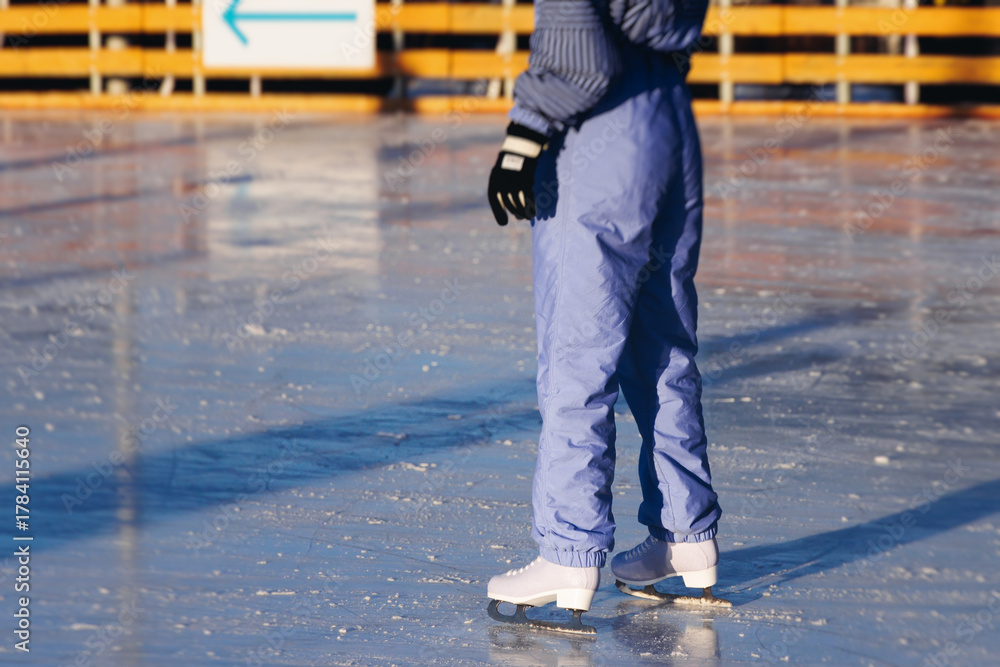 Obraz premium Ice skating on the ice rink arena with people, skating rink surface, ice skating in winter city, winter activities, holiday christmas time, with new year decoration and illumination, ice skates boots