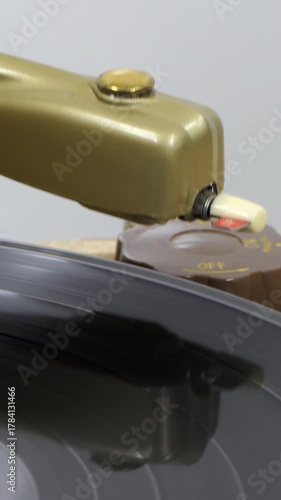 Vintage turntable with record album and needle dropping. Vertical view.  