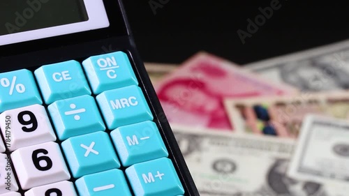 回転する紙幣（日本円、米ドル、人民元）と計算機　