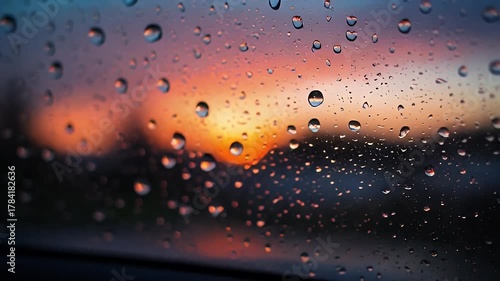 Raindrops On A Car Window With A Blurry Sunset Sky And Orange Bokeh Lights In The Background During Dusk