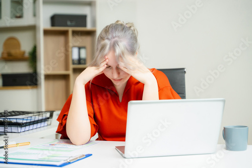 Foto Overwhelmed young woman stressed at her desk with a laptop and reports in a modern office
