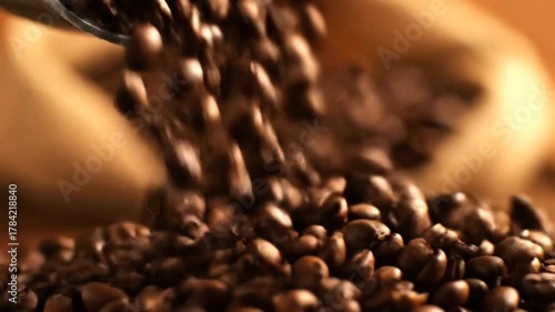 Close-up of coffee beans being poured from a scoop onto a wooden surface, with blurred bags in the background