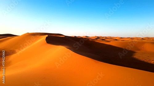 Expansive golden sand dunes under a clear blue sky, showcasing the serene beauty of the desert landscape