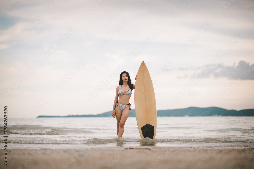 Fototapeta premium Sexy woman holding surfboard sport related to surfing vacations healthy living and active beach lifestyle.