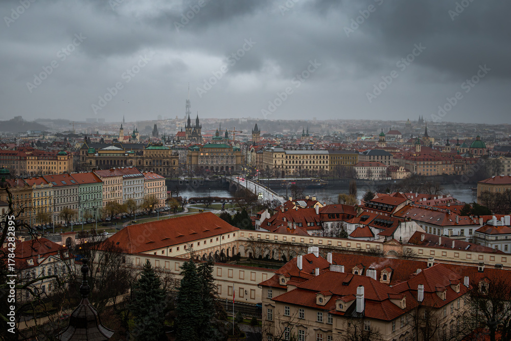 Obraz premium Prague city and river appear mysterious beneath foggy, darkened skies.