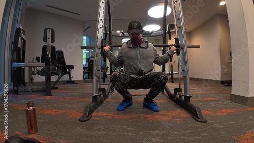 Man Performing Barbell Squats on a Smith Machine


