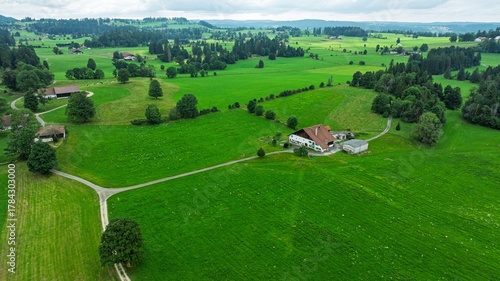 Canvas Print Drone shot of the picturesque Swiss countryside featuring a quaint farmhouse surrounded by lush green fields and rolling hills