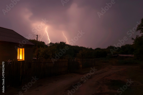 Night thunderstorm with lightning and thunder over the village in summer