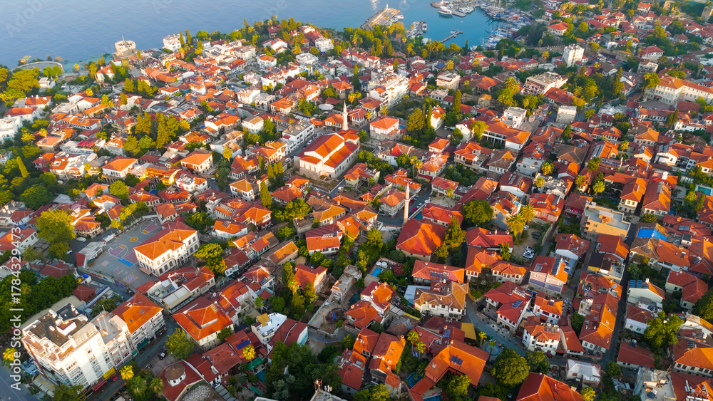 Fototapeta premium Antalya, Turkey. Aerial view of Kaleici Old Town with narrow streets, terracotta roofs, lush green trees along Mediterranean coastline in morning light.. Aerial View