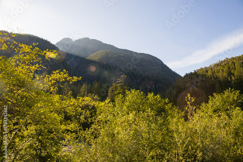 Beautiful sunny sunset in the mountains. Rays pass through the trees and the mountains cast shadows - summer hike in British Columbia, Canada