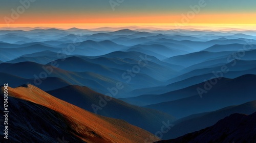 Vast mountain range at dawn/dusk, warm light on foreground peak, hazy blue distant peaks