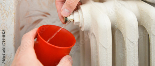 Évacuation de l'air d'un radiateur en fonte jusqu'à ce que l'eau coule en continu, format bannière
