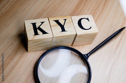 Know your customer or KYC concept with magnifying glass and wooden blocks.