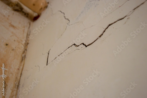 A close-up view shows significant cracks in the wall of an aging building, indicating disrepair and the need for maintenance