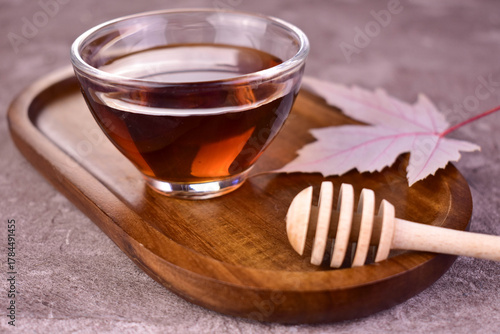 Maple syrup in a glass bowl on a wooden background.
