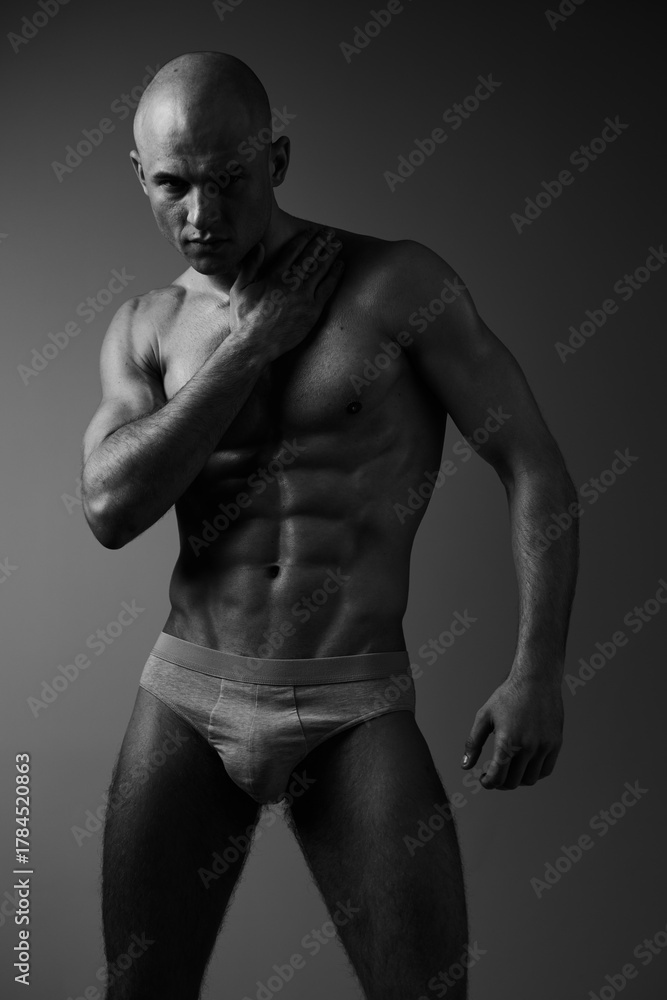 Fototapeta premium Athletic man posing in striking black and white photography, showcasing strength and confidence through dynamic body posture and expression.