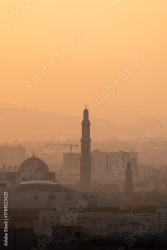 Muscat city skyline with mosque and minaret at sunset