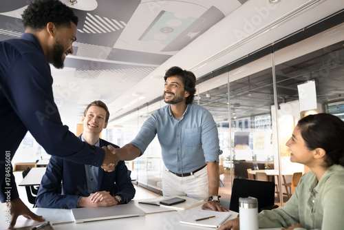 Happy multiethnic business partners handshake on group meeting in office
