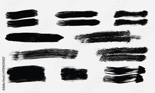 Set of grunge paint brush stroke elements and abstract black splatters on a white background for graphic design