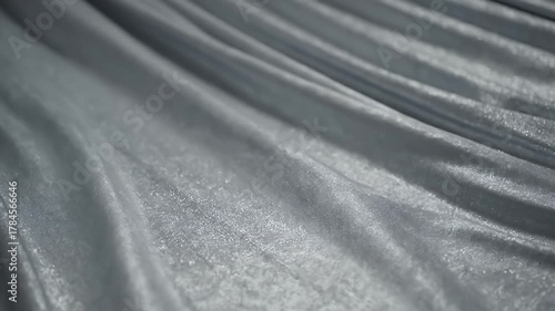 Close-up of flowing silver fabric with subtle pink undertones and soft lighting.