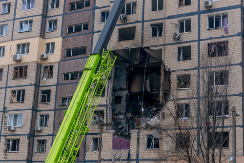 A fragment of the facade of an apartment building, showing extensive damage as a result of an explosion or shelling. The breach in the wall spans several floors and reveals the destroyed interior.