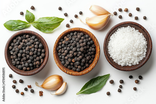 A vibrant flat lay featuring black peppercorns, garlic, and fresh basil leaves in wooden bowls, showcasing culinary ingredients.