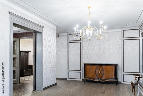 retro interior of large bright living room. Wooden furniture, large chandelier on ceiling, retro chest of drawers. lot of light in room. Illuminated by lamp. Architecture inside home