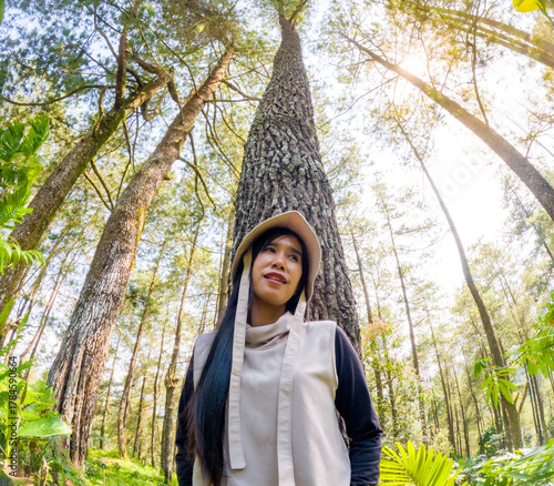 Принти на полотні Asian woman leaning against a pine tree, applying Japanese bathing forest