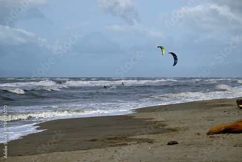 Kitesurfing at italian beach. Some kitesurfers at Torre del Lago beach, tuscany, italy. Some are junping out of the water. Mediterraenean Sea.