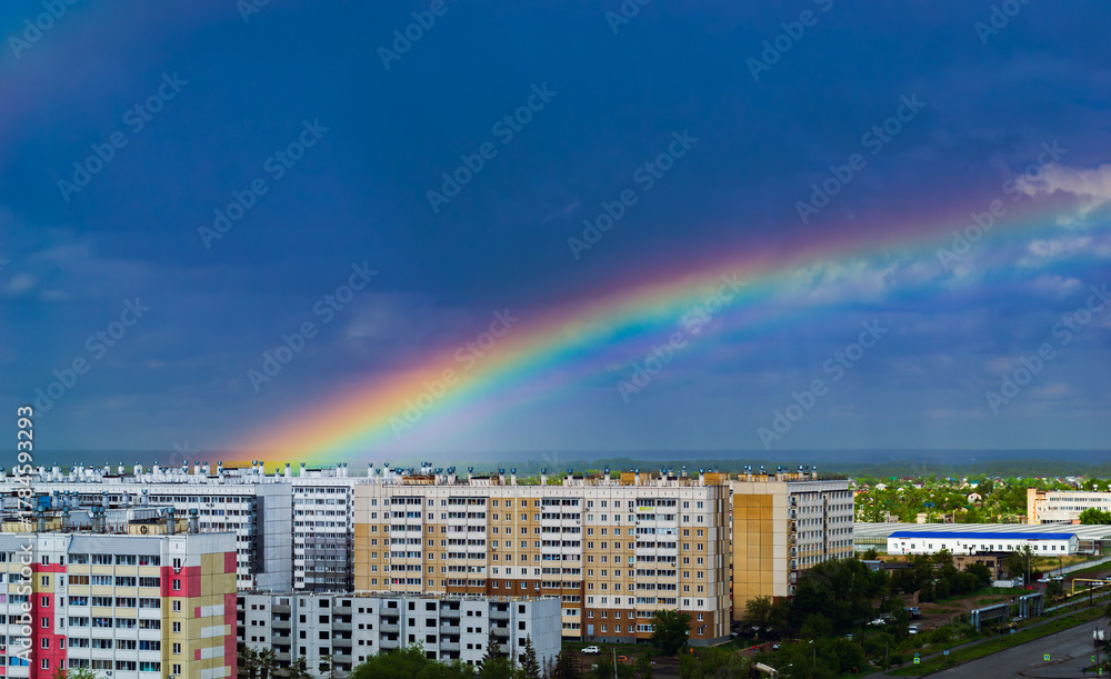 Obraz premium Fantastic beautiful rainbow over city buildings after rain