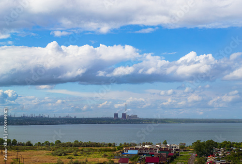Power plant by lake under bright beautiful clouds