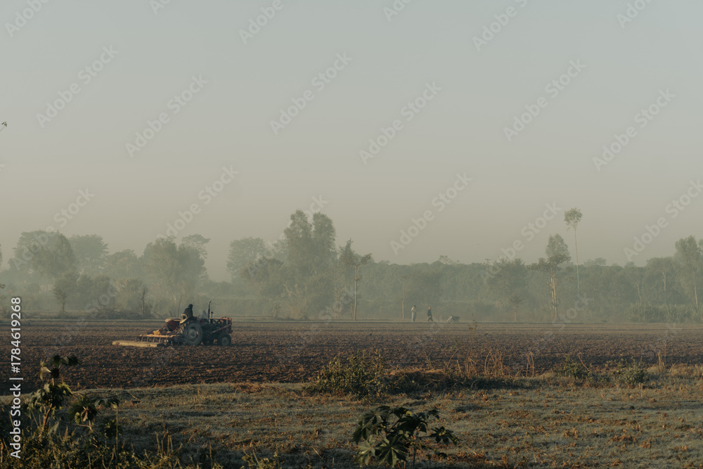 Fototapeta premium Tractor plowing rural field agriculture farm landscape farming machinery cultivation soil land work day
