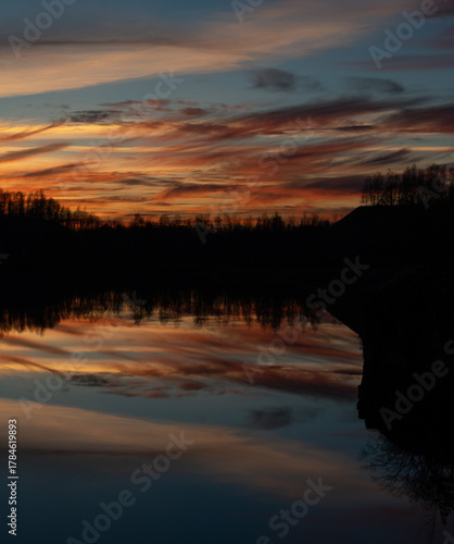 Beautiful sunset and trees reflecting in calm water