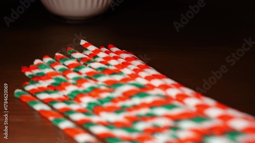 Christmas color theme striped pipe cleaners on dark wooden oak table top in warm candle light