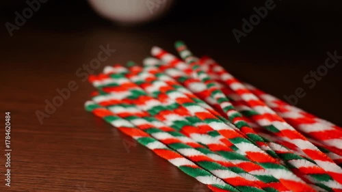 Christmas color theme striped pipe cleaners on dark wooden oak table top in warm candle light
