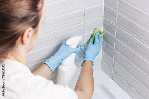 Wallpaper Mural Woman cleaning bathroom tiles with spray bottle and sponge. Hygiene and housework concept with hand in rubber gloves. Domestic cleaning and disinfection process closeup. Torontodigital.ca