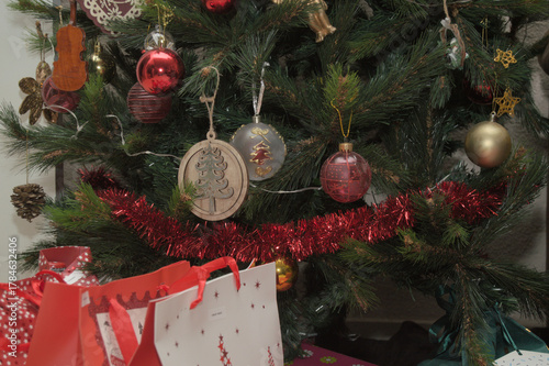 Decorated Christmas tree with ornaments, tinsel, and gift bags creating a festive holiday atmosphere.