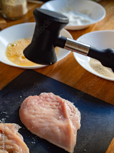 Cooking breaded chicken cutlets- pounding chicken breast, close-up