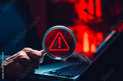 Cyber threat detection and data risk warning concept. Person holding magnifying glass with digital alert symbol representing cybersecurity breach, malware investigation, system vulnerability analysis,