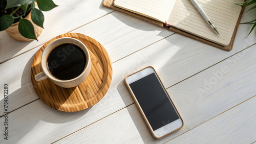 A comforting cup of coffee steaming, notebook and smart phone on a worn wooden table 