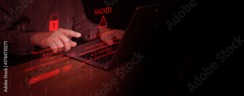 Hands using laptop with hacking alert and access denied message on screen, representing password breach, account compromise, identity theft, cybersecurity threat, data stealing, and online fraud.