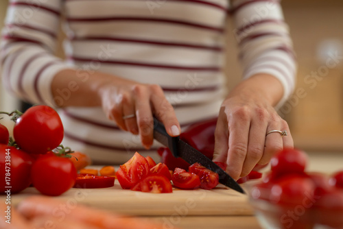 Woman cutting fresh tomatoes on wooden board