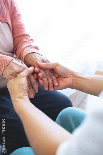 A woman holds hands and gives love to her elderly mother at home, creating bonding and happiness. love and care concept