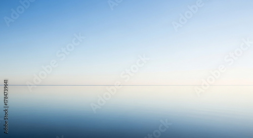 Fototapeta Naklejka Na Ścianę i Meble -  Calm ocean reflecting the clear blue sky with a subtle horizon line view