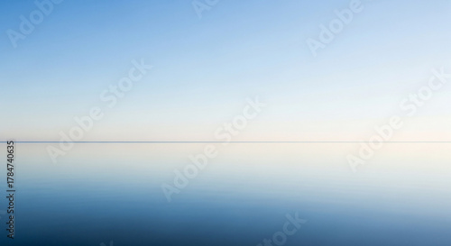 Fototapeta Naklejka Na Ścianę i Meble -  Still blue ocean and clear sky meet at the horizon on a bright day